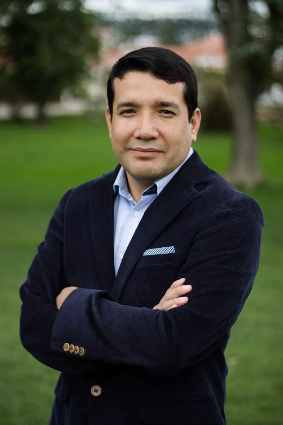 Colombian man in suit smiling with folded arms