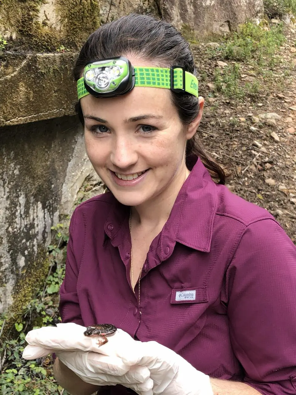 Woman with headlamp holding salamander