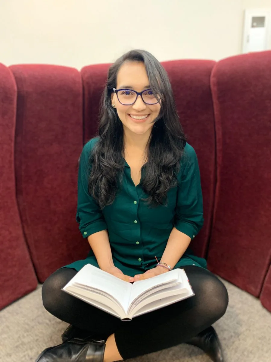 Colombian woman smiling while sitting in a red chair with an open book